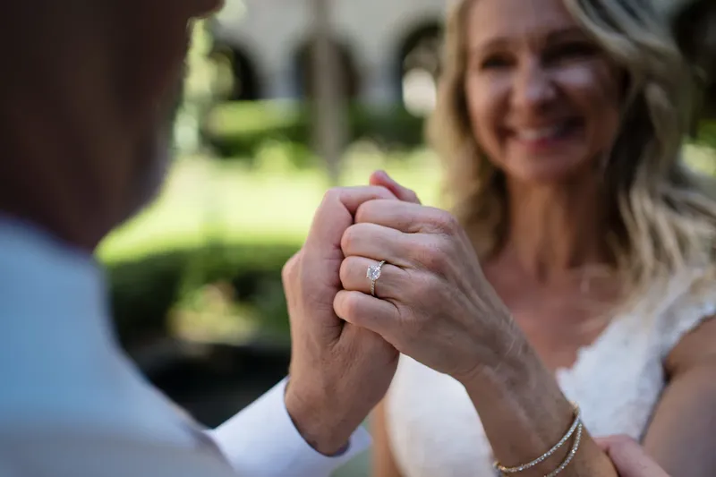 Detail shot of hands clasped showing oval engagement ring with pave band