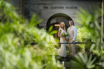Couple on the bridge with The Lightner Museum sign visible through greenery