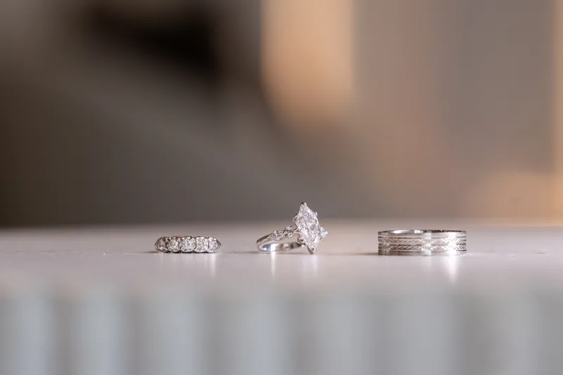 Three wedding rings including marquise-cut engagement ring on marble surface