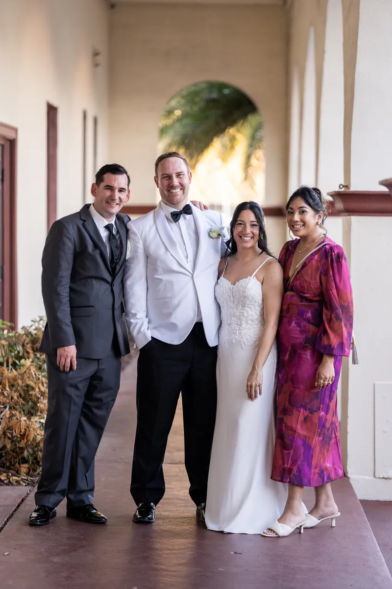 Couple posing with friends in covered walkway after ceremony