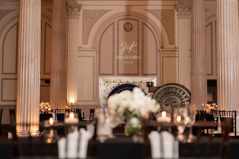 Reception detail with J and K monogram projected on wall behind Treasury bank vault door