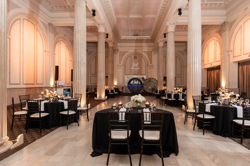 Wide shot of Treasury reception hall with black linens, candlelit tables, and grand columns