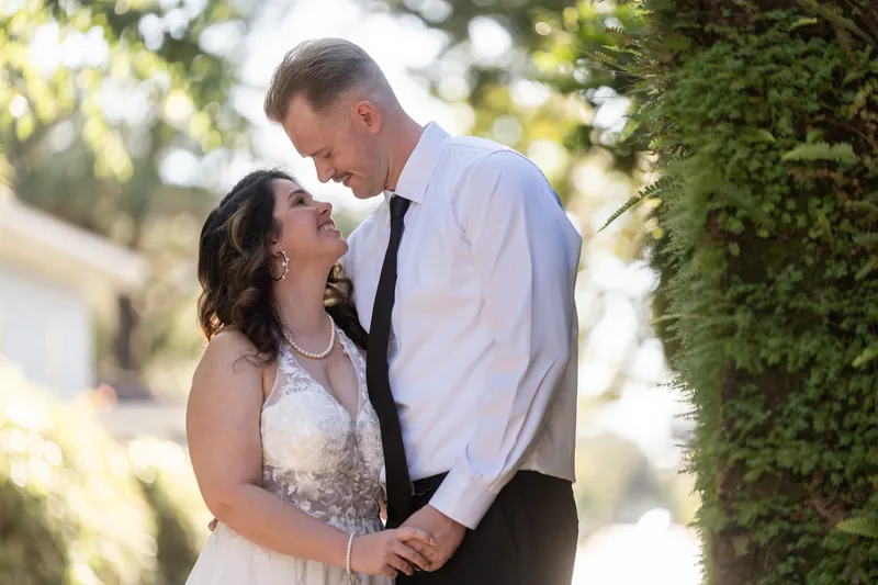Two people lean in close beneath dappled tree shade, sharing an intimate moment in downtown St Augustine.