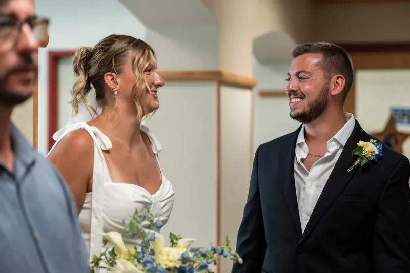 Kalsey and Matt smile at each other during their ceremony at St. Johns County Courthouse, with guests visible nearby.