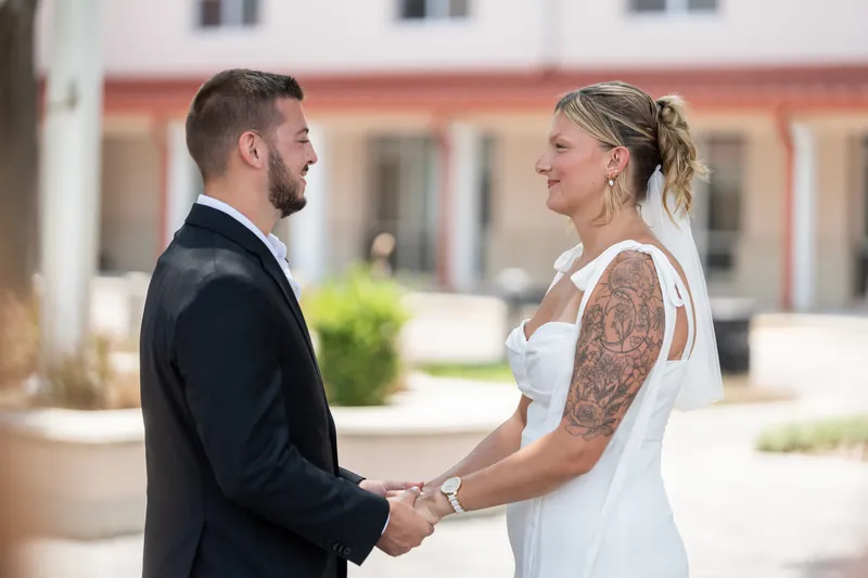 Matt and Kalsey hold hands outside the courthouse, facing each other in the bright afternoon sun.