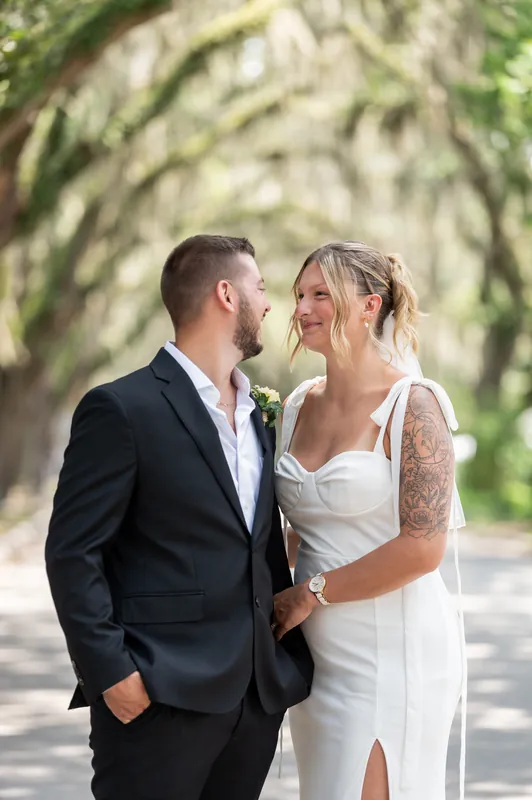 Matt leans in close to Kalsey, who smiles warmly, framed by the draped greenery above them.