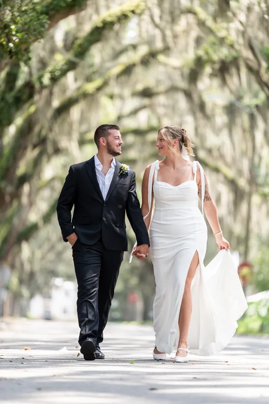 The couple walks hand in hand down the Spanish moss-draped street, Kalsey's white dress flowing as they move forward.