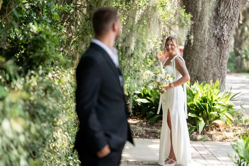 Matt faces Kalsey across a brick pathway lined with greenery and moss-draped branches in their St. Augustine setting.