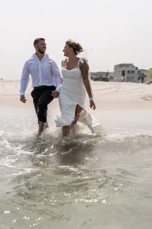 Matt and Kalsey wade into the ocean together, their white clothing contrasting with the shallow turquoise water at Vilano