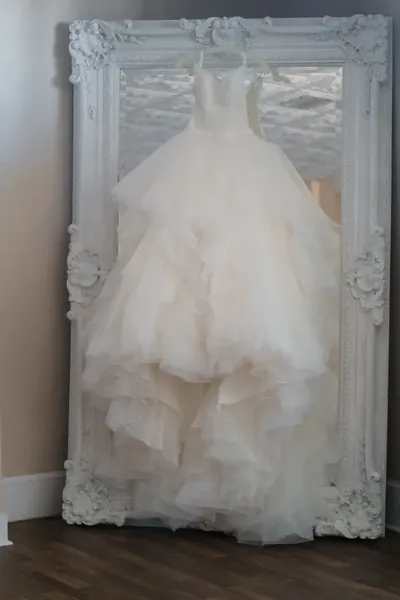 Elegant white wedding gown displayed in ornate decorative frame