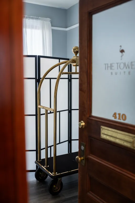 A brass garment rack stands in a hotel hallway outside room 410 at The Treasury on the Plaza.