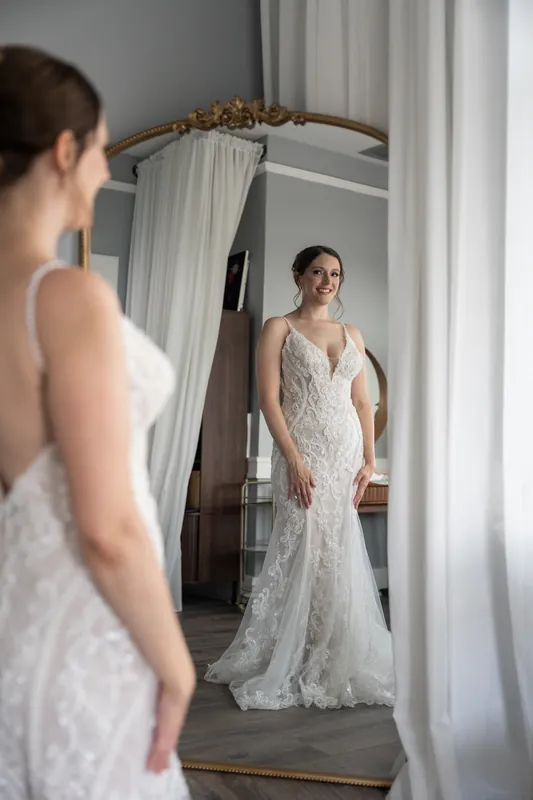 Katherine examines her reflection in a mirror while wearing her embellished lace gown at The Treasury on the Plaza.