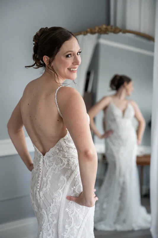 Katherine smiles over her shoulder, showing the low back detail of her beaded wedding dress at The Treasury on the Plaza.