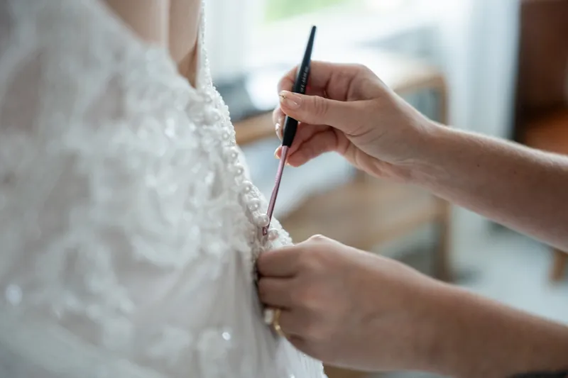 Someone's hands use a brush to add finishing touches to Katherine's lace dress fabric at The Treasury on the Plaza.