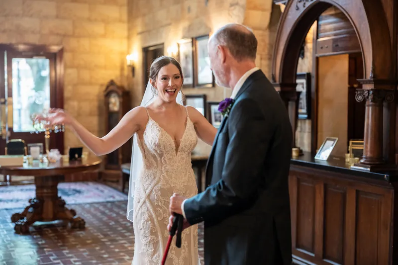 Katherine and Nathan face each other under the stone arches at The Treasury on the Plaza, exchanging their first look before