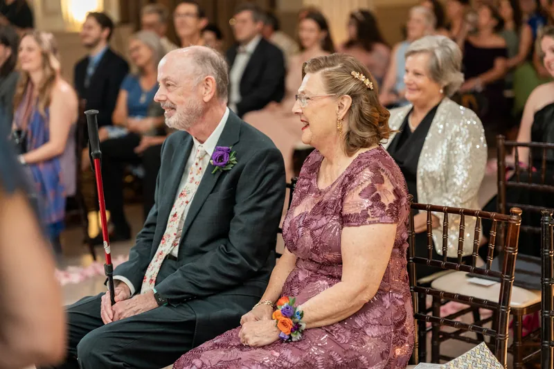 A guest in a burgundy dress beams while seated in the audience, watching the ceremony unfold at The Treasury on the Plaza.