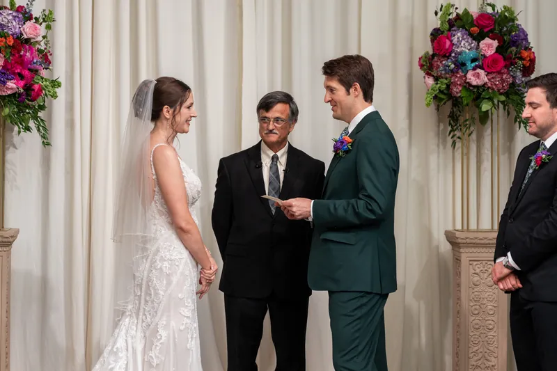 Katherine and Nathan exchange vows before an officiant at The Treasury on the Plaza, flanked by groomsmen in dark suits.