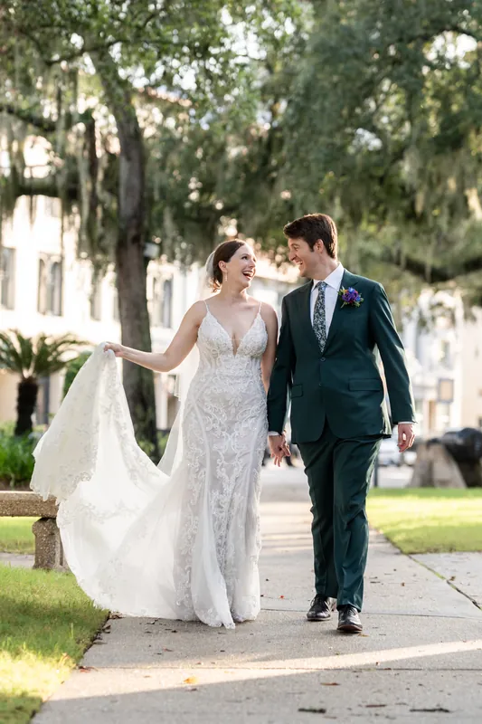 Katherine in her lace gown and Nathan in his dark suit stand at the St. Augustine Bayfront railing, boats and water visible