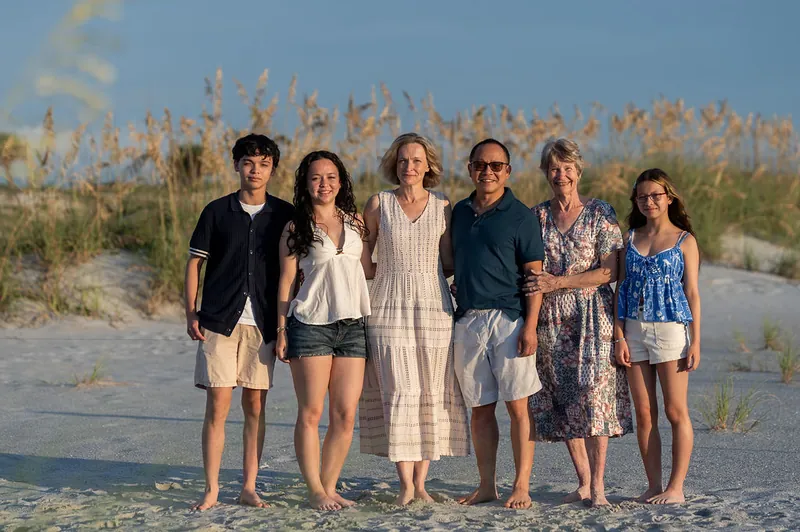 Six family members of varying ages stand in a line on the sand at Vilano Beach, wearing casual summer attire.