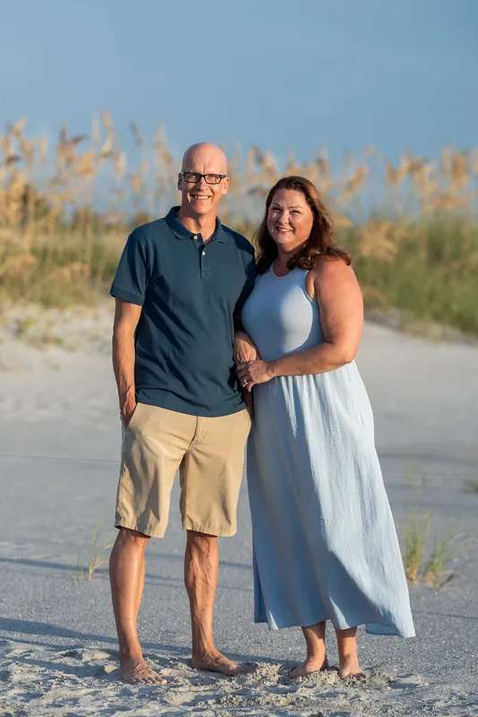 A man and woman stand close together on the sand at Vilano Beach, the woman wearing a light blue dress.
