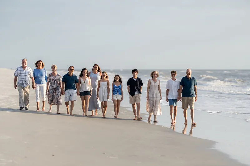 Extended family of about 15 people stand in a line along the wet sand at Vilano Beach, facing the camera with the Atlantic