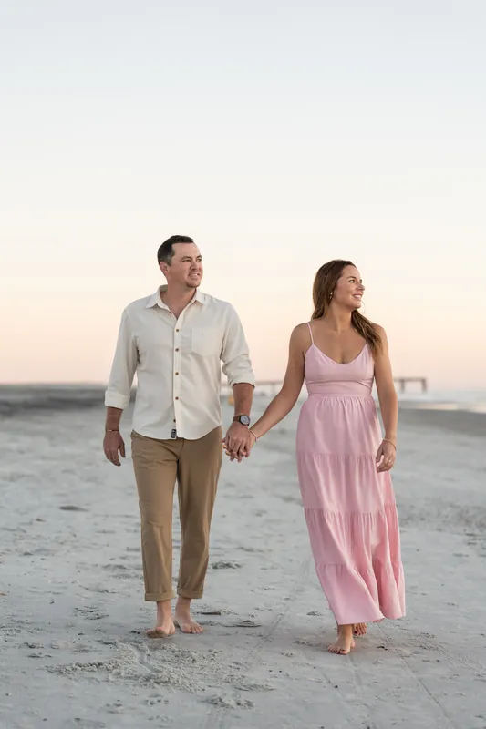 Kelly and Jereme walk hand in hand barefoot along the shore at Vilano Beach at sunset.