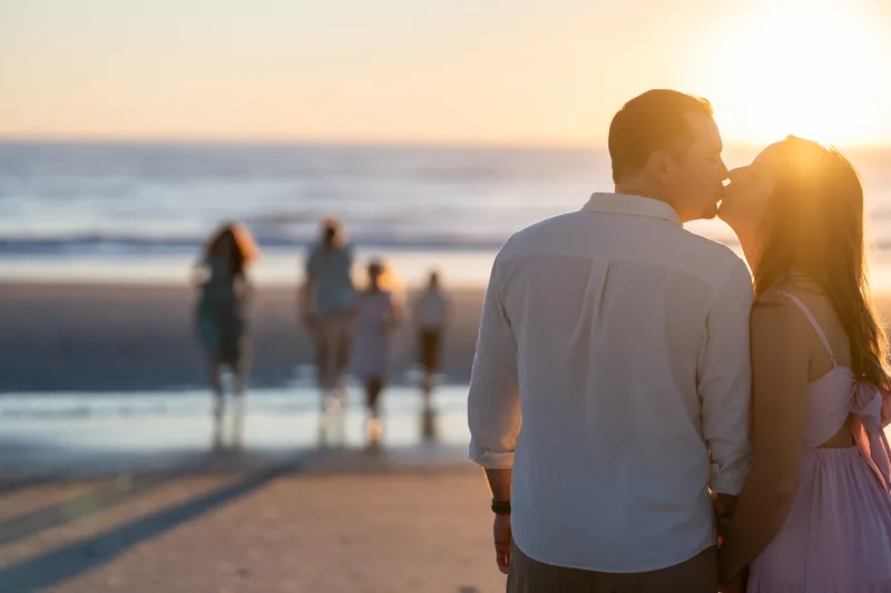 The couple stands close together in the foreground while their family wades in the background at Vilano Beach.