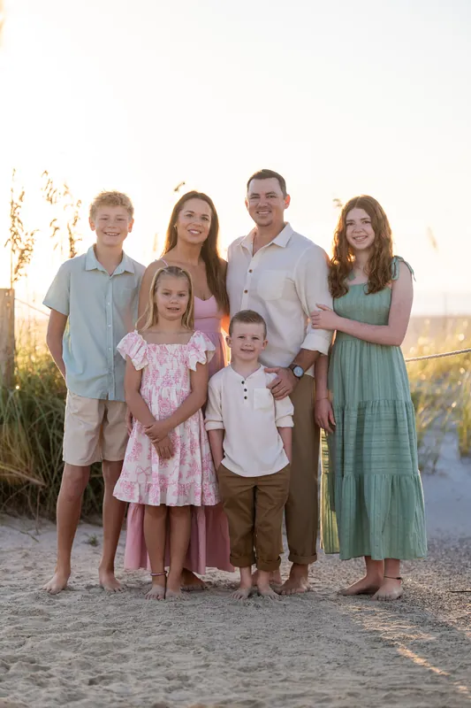 Kelly and Jereme stand with four children of varying ages on the sand at Vilano Beach, bathed in warm sunset light.