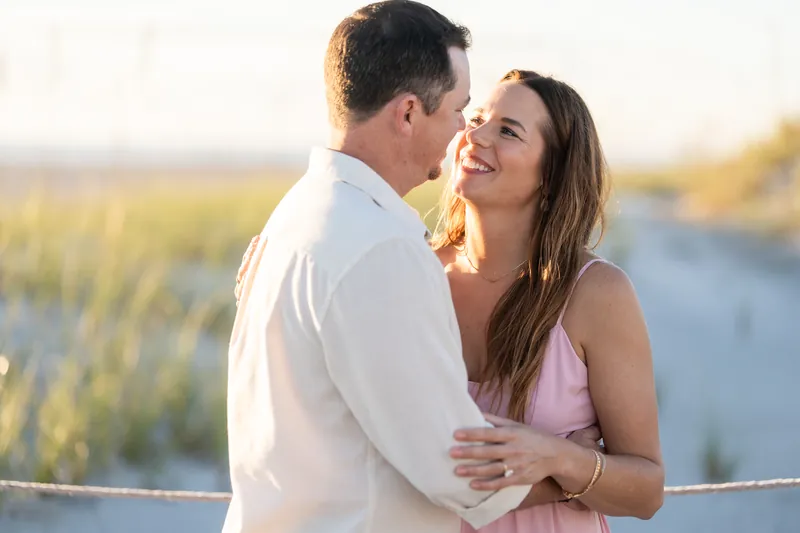 The couple embrace as golden hour light bathes the marsh grasses behind them at Vilano Beach.