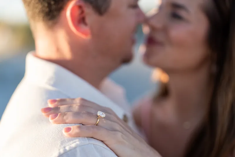 Close-up of a hand with a diamond ring resting on someone's shoulder during a moment at Vilano Beach.