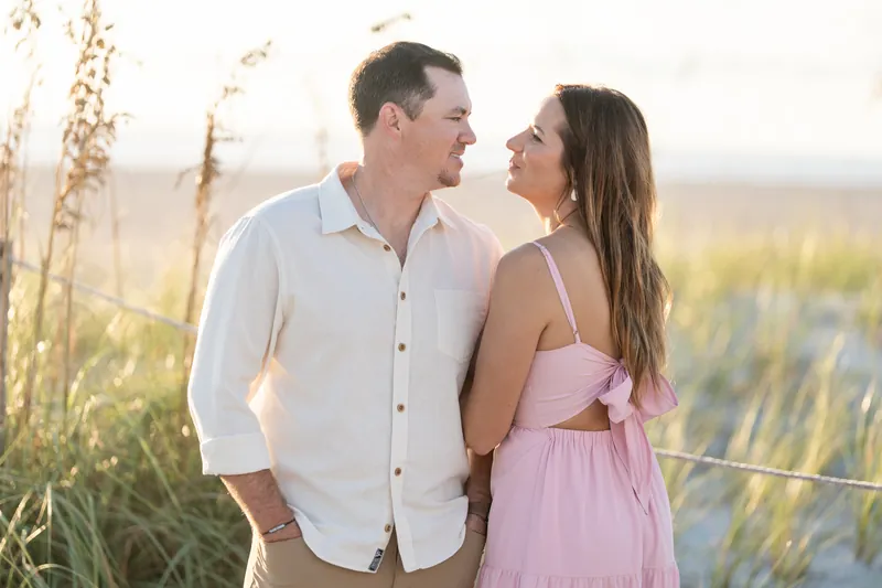 A couple stands together among dried marsh vegetation at Vilano Beach, facing each other as evening light wraps the scene.