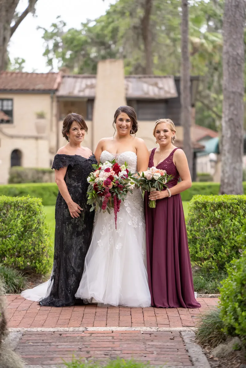 Scott holds Kelsey close as they pause mid-aisle, her rose bouquet visible while guests applaud around them.