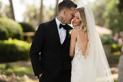 Groom kissing bride's cheek in garden setting on wedding day