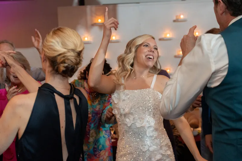 Kerry in a sequined white dress dances with arms raised among guests at Casa Monica Resort & Spa's reception.
