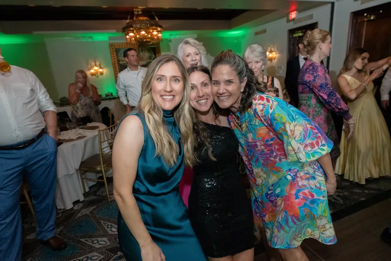Three women in colorful outfits smile at the camera during the reception at Casa Monica Resort & Spa.