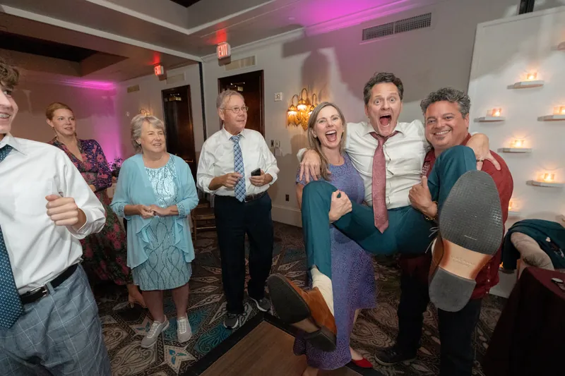 A group of family members and friends pose together, arms linked, enjoying the celebration at the reception.