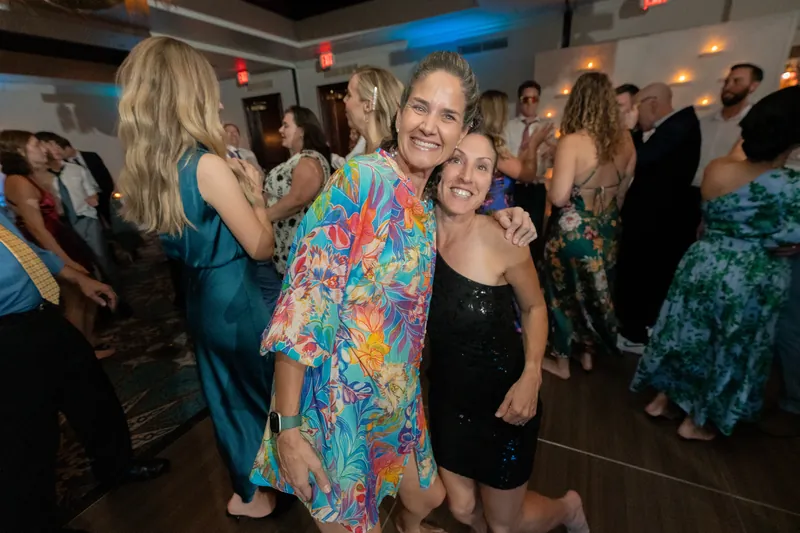 Kerry hugs a guest in a colorful floral dress while dancing at the reception.