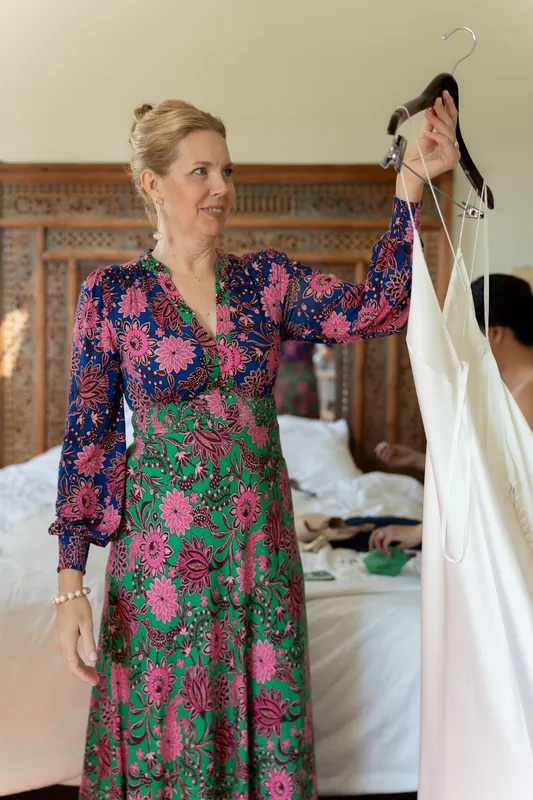 Woman in a colorful floral dress holds up a white garment at Casa Monica Resort & Spa.