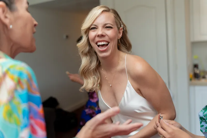 A woman in a white halter top laughs while talking with a guest at Casa Monica Resort & Spa.