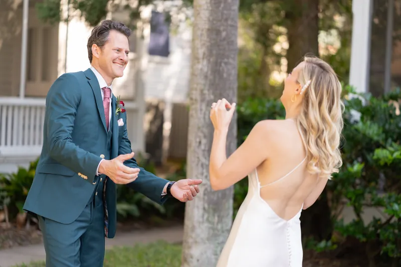 Rhett and Kerry hold hands and laugh together on the grounds, with palm trees and architecture visible behind them.