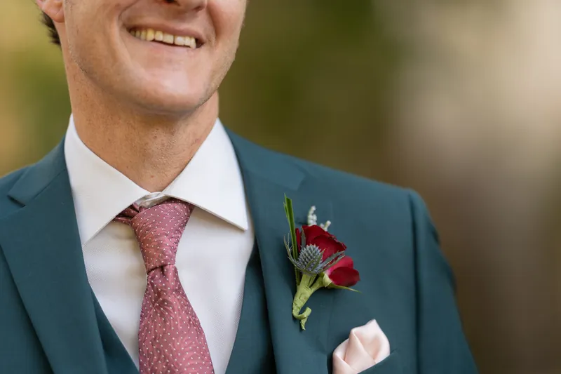 Rhett's chest-level portrait shows his burgundy tie, white dress shirt, and red carnation boutonniere against a blurred