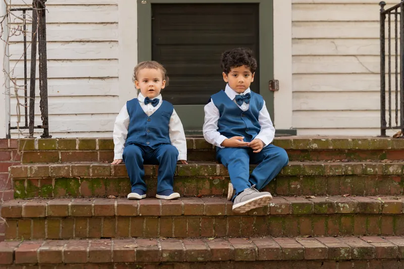 Two young children in matching blue vests and white shirts sit on brick steps at Casa Monica Resort & Spa.