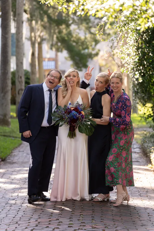 Five adults laugh and pose on a sunny brick walkway lined with ivy-covered walls at the resort.
