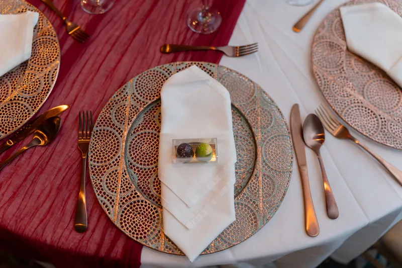 Formal place setting at Casa Monica Resort & Spa features patterned charger plates, white napkins with small floral detail