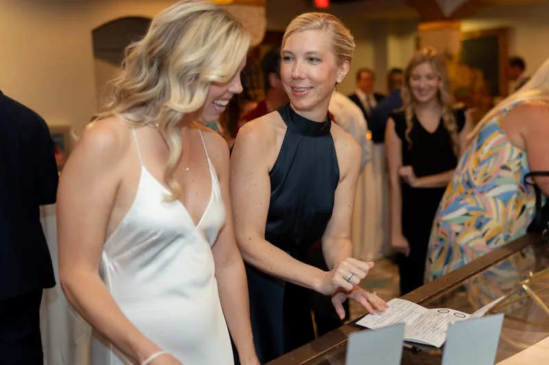 Kerry and a guest in a black sleeveless top chat while holding a program at Casa Monica Resort & Spa.