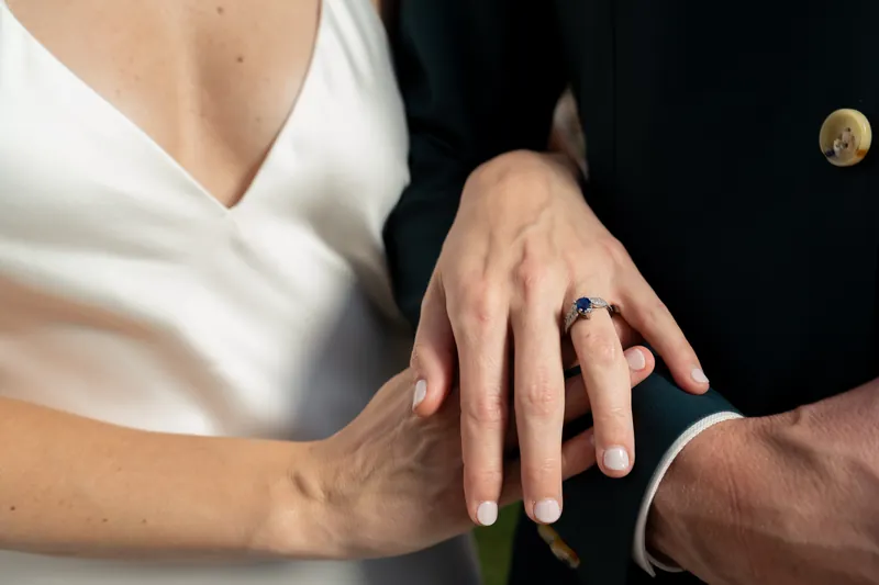 Their hands meet, displaying matching wedding bands in close detail.