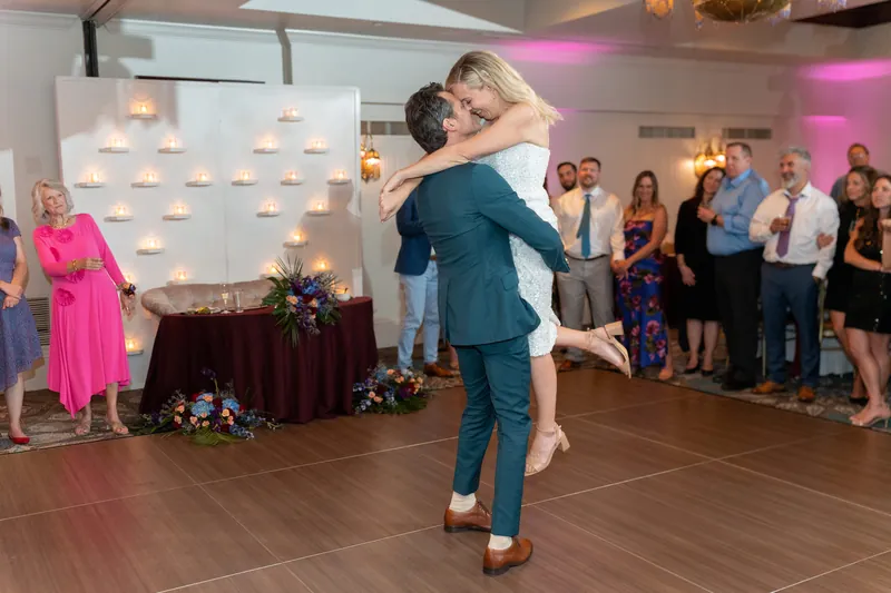 Rhett carries Kerry in their arms during an exuberant dance lift as wedding guests watch from the perimeter.