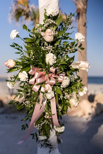 Elegant beach wedding floral arrangement with white carnations and pink ribbon