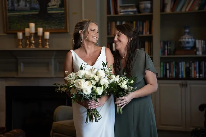 Bride and bridesmaid sharing a joyful moment with bouquets