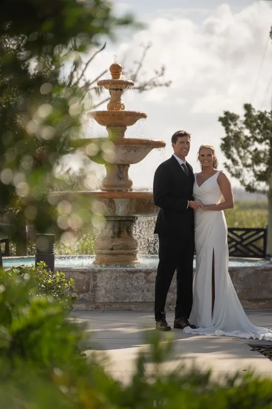 Newlyweds posing by fountain at River House